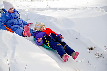 Image showing Two girls rolling down a hill in snow