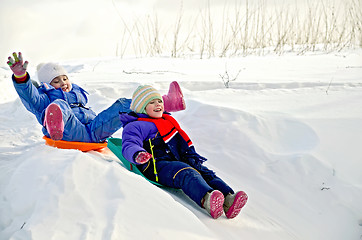 Image showing Two little girls on sled through the snow to slide