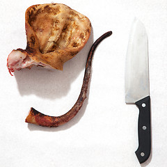 Image showing pork ears with knife and blood white background.