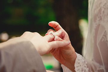 Image showing mans hand putting a wedding ring on the brides finger