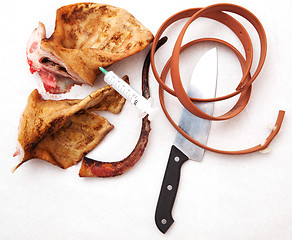 Image showing pork ears with knife and blood white background.