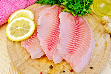 Image showing Tilapia with parsley and lemon on board