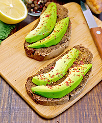Image showing Sandwich with avocado and lemon on board