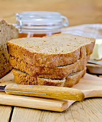 Image showing Rye homemade bread with honey and knife on board