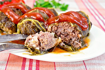 Image showing Rhubarb leaves stuffed with fork in plate on tissue