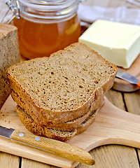 Image showing Rye homemade bread with honey and butter on board