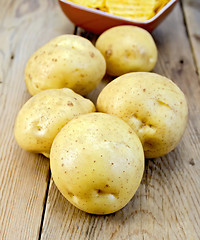 Image showing Potatoes yellow and chips on wooden board