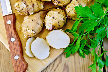 Image showing Jerusalem artichokes cut with knife and parsley on board