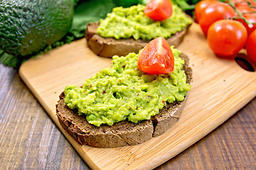 Image showing Sandwich with guacamole and tomatoes on dark board