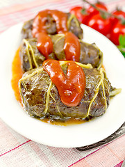 Image showing Rhubarb leaves stuffed with sauce in plate on tissue