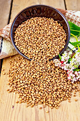 Image showing Buckwheat in brown bowl with flower and towel on board