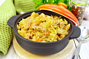 Image showing Cabbage stew with meat in black brazier on light board