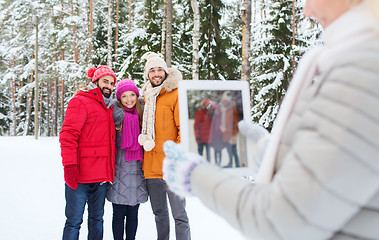 Image showing smiling friends with tablet pc in winter forest