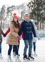 Image showing happy friends ice skating on rink outdoors