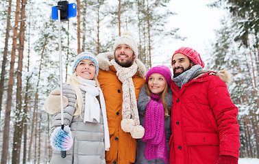 Image showing smiling friends with smartphone in winter forest