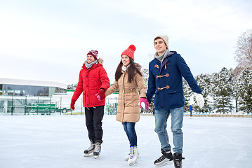 Image showing happy friends ice skating on rink outdoors