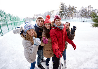 Image showing happy friends with smartphone on ice skating rink