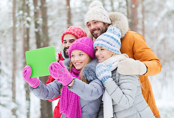Image showing smiling friends with tablet pc in winter forest