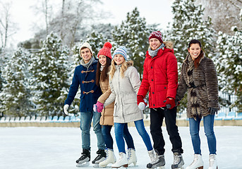 Image showing happy friends ice skating on rink outdoors