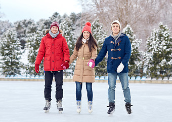 Image showing happy friends ice skating on rink outdoors