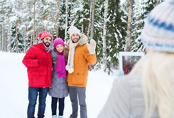 Image showing smiling friends with tablet pc in winter forest