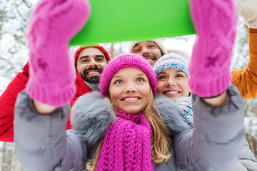 Image showing smiling friends with tablet pc in winter forest