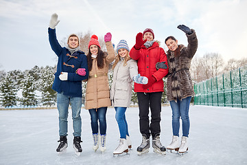 Image showing happy friends ice skating on rink outdoors