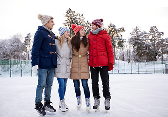 Image showing happy friends ice skating on rink outdoors