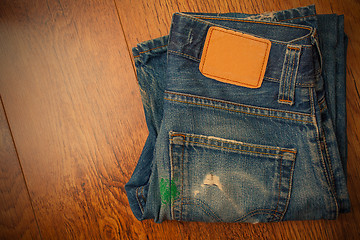 Image showing old blue jeans with brown label on the belt smeared with green p