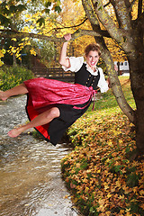 Image showing Playful young woman swinging on a tree