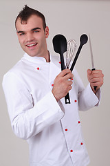 Image showing Happy chef holding various kitchen utensils