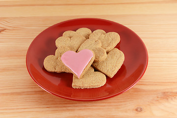 Image showing Iced and plain heart-shaped biscuits piled on a red plate 