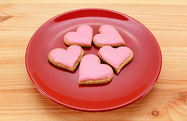 Image showing Five heart-shaped iced cookies on a red plate 