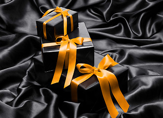 Image showing Black gift boxe with yellow satin ribbons and bow
