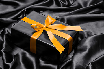 Image showing Black gift box with yellow satin ribbon and bow