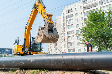 Image showing Using of excavator as crane for raising of tube