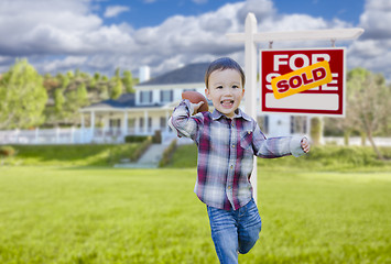 Image showing Boy Playing Ball in Yard Near Sold Real Estate Sign