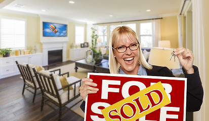 Image showing Young Woman Holding Sold Sign and Keys Inside Living Room