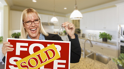 Image showing Young Woman Holding Blank Sign and Keys Inside Kitchen