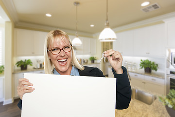 Image showing Young Woman Holding Blank Sign and Keys Inside Kitchen