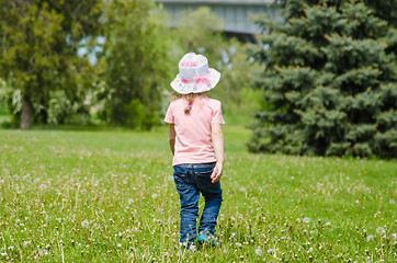 Image showing Girl walking on the grass with dandelions