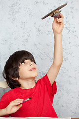 Image showing boy in a red shirt with a wooden plane