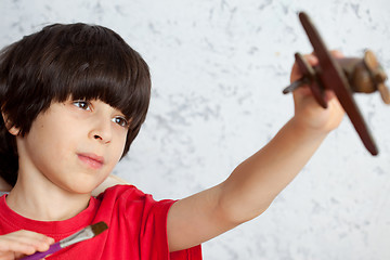 Image showing portrait of a boy with a wooden plane and brush