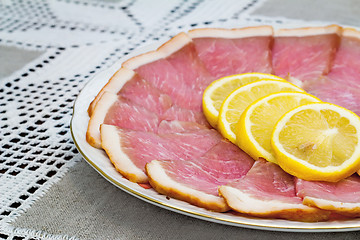 Image showing The dish with slices of ham and lemon 