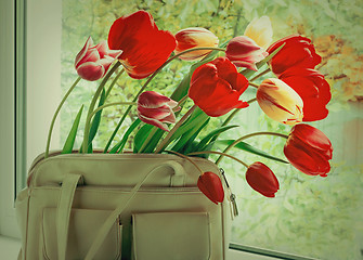 Image showing Flowers tulips and a women bag on a window window sill.