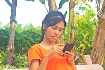 Image showing Young girl sitting on the wooden swing with mobile phone