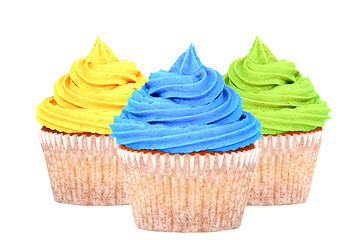 Image showing Three cupcakes with yellow, blue and green icing