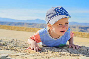 Image showing Smiling little boy laying down on the rock