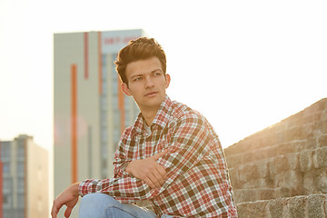 Image showing Handsome man outdoors sitting on stone stairs