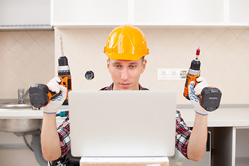 Image showing repairman with a drill near a computer